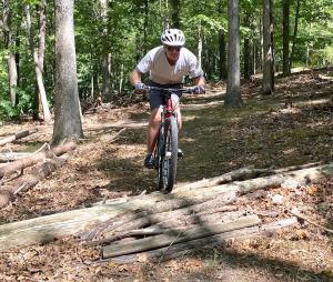 a man riding a bike on a trail in the woods at Hot Tub, Deck, Grill, Fire Pit, Game Room & WiFi in Great Cacapon