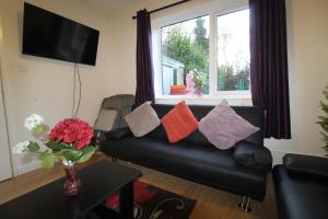 ein Wohnzimmer mit einem schwarzen Ledersofa und bunten Kissen in der Unterkunft Keswick House Chesterfield by Smart Corporate Stays in Newbold