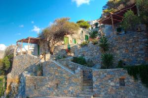 a stone building with stairs and plants on a hill at Pano Gitonia in Aegiali