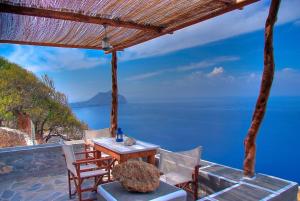 una mesa y sillas en un balcón con vistas al océano en Pano Gitonia en Aegiali