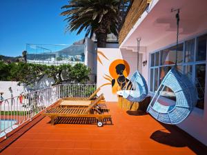 a porch with two benches and a mural of a woman at Beachwave Camps Bay in Cape Town +68 photos