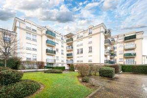 a large white apartment building with a courtyard at Family Travel Paris 4 in Bussy-Saint-Georges
