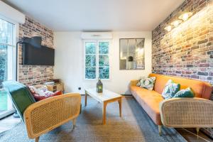 a living room with a couch and chairs and a brick wall at Family Travel Paris 4 in Bussy-Saint-Georges