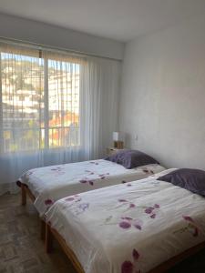 dwa łóżka ustawione w pokoju z oknem w obiekcie Appartement vue sur mer, proche Croisette w Cannes +11 zdjęć