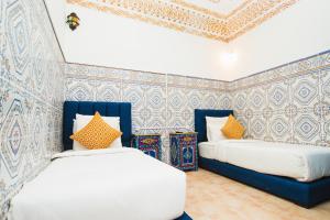 two beds in a room with blue and white wallpaper at Riad Dar Kella in Marrakech