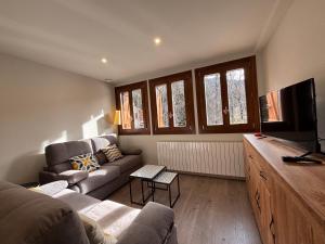 a living room with a couch and a flat screen tv at BPirineos-La Solana in Benasque +4 photos