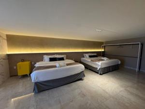 a hotel room with two beds and a yellow wall at HOTEL NOVO CENTRO in Petrolina