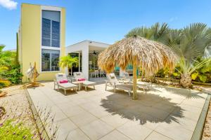 a patio with chairs and a straw umbrella at Delfins Residences in Kralendijk