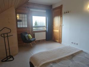 una camera da letto con un letto, una sedia e una finestra di Le Ptit Beccon a Cruseilles