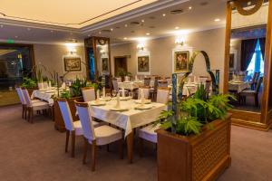a restaurant with white tables and chairs and plants at Hotel Sevlievo Plaza in Sevlievo