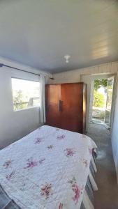 a bedroom with a bed and a wooden cabinet at Casa pé na areia in Hermenegildo