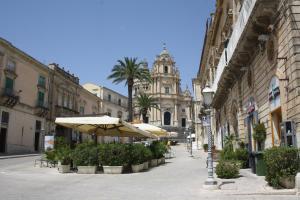 an empty street with umbrellas and palm trees and a building at La Chiave di Volta in Ragusa