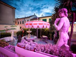 une statue rose d'une femme nue dans un jardin dans l'établissement Hotel Sileoni Dépendance Villa Antonio, à Marina di Cecina