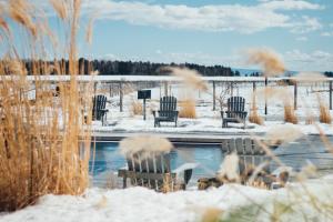 a snow covered yard with chairs and a pool at Hôtel & Spa Le Germain Charlevoix in Baie-Saint-Paul