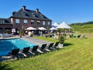 a large house with chairs and a swimming pool at Domaine de La Noiseraie in Rhisnes