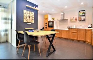 a kitchen with a wooden table and a clock on the wall at Maison de Village 4 chambres in Sabran