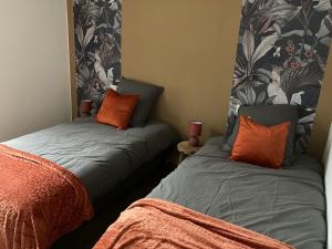 a bedroom with two beds with orange pillows and a mirror at Villa de Rospico Les villas de Nevez in Névez