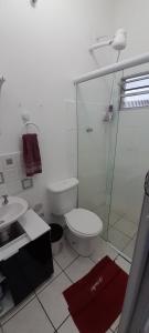 a bathroom with a toilet and a glass shower at Flat no centro de pindamonhangaba in Pindamonhangaba