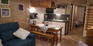 a small kitchen with a table and a blue couch at LOGEMENT 4 PERSONNES in Orcières