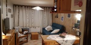 a living room with a blue couch and a table at LOGEMENT 4 PERSONNES in Orcières