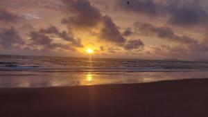 a sunset on a beach with the ocean at Apto 20 QUADRA PRAIA CISSA in Itapoa +8 photos