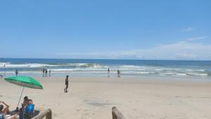 a group of people on a beach with an umbrella at Apto 20 QUADRA PRAIA CISSA in Itapoa