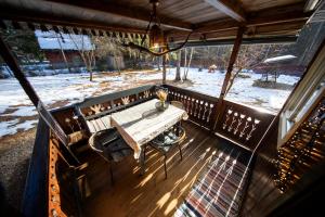 a porch with a wooden table and a snow covered yard at Cabana Adrienne in Izvoru Mureşului