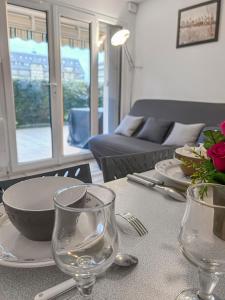 a table with plates and glasses on top of it at Grande terrasse privée à 5min de la Plage à pied in Villers-sur-Mer