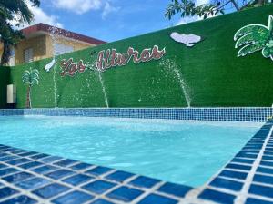 a swimming pool with a sign on a green wall at Las Alturas Loft 304 in Aguadilla