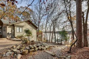 una pequeña casa en el bosque con una pared de piedra en Lakefront Hot Springs Village Home with Private Dock, en Hot Springs Village