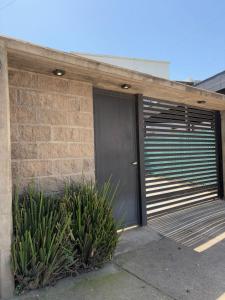 un garage con una porta nera e alcune piante di Casa ALI, cuenta con 4 camas individuales y una cama matrimonial, capacidad máxima 6 personas a Yerba Buena