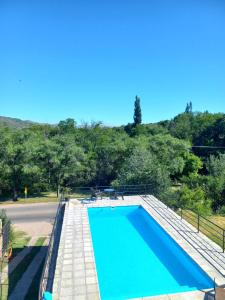 a blue swimming pool with trees in the background at Complejo vacacional Piedra&Sol in Trapiche