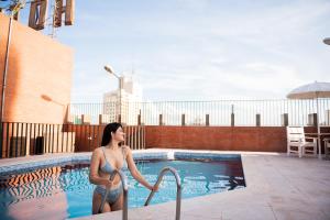 a woman in a bikini standing next to a swimming pool at Aruá Hotel, Restaurante e Convenções in Presidente Prudente