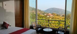 a bedroom with a view of a mountain from a window at Chill Breeze Paradise in Yelagiri