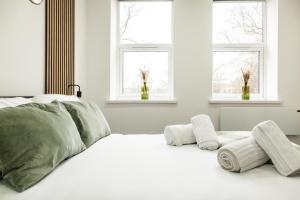 プレストンにあるComfortable Apartment in desirable area of Prestonの白いベッド1台(窓2つ付)が備わるベッドルームです。