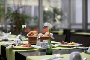 a table with plates of food and a basket of bread at IntercityHotel Wien in Vienna
