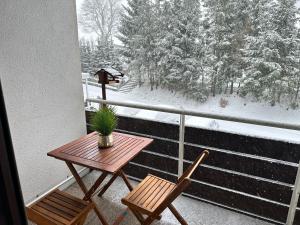 a table and two chairs on a balcony with snow at Jacky Wohnung in Schonwald im Schwarzwald