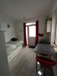 a bedroom with a bed and a table and a window at Le kiosque de la villa des roses charmant et atypique in Nozay