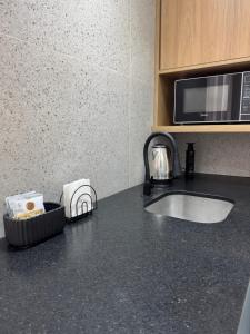a kitchen counter with a sink and a microwave at Studio no centro, confortável e prático in Florianópolis