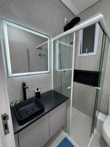 a bathroom with a sink and a glass shower at Studio no centro, confortável e prático in Florianópolis +21 photos