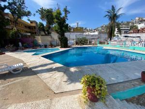 a swimming pool with blue water in a resort at Hotel Walton in Acapulco