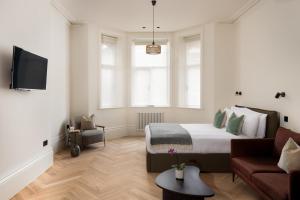 Un dormitorio blanco con una cama y un sofá. en FiveM West Hampstead - North, en Londres