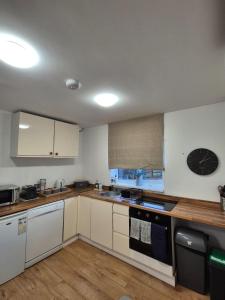 a kitchen with white cabinets and a clock on the wall at Rosies Retreat 2 Bedroom Farm Cottage in Preston Bisset