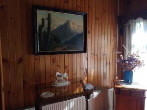 a painting on a wooden wall with a table with a statue at La Posada del Colono in Puerto Clocker