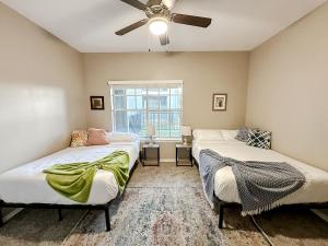 Sleepover 1BD 1BA Corpus Christi Apartments في كوربوس كريستي: سريرين في غرفة مع مروحة سقف