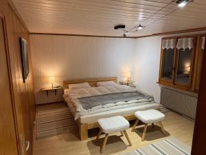 a bedroom with a large bed and two chairs at Enzian 4 Zi Ferienwohnung in Landhaus in Frutigen