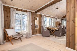 ein Esszimmer mit Tisch und Stühlen und Fenstern in der Unterkunft Moderne hytte plass for 10 in Rendalen