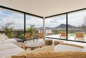 un salon avec des meubles blancs et de grandes fenêtres dans l'établissement Villa Calma by Aura Collection, à Lajares