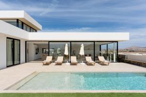 une maison avec une piscine et des chaises longues dans l'établissement Villa Calma by Aura Collection, à Lajares