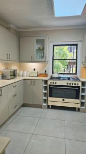 a white kitchen with a stove and a window at BestPlaceEver - Luxury House with Vineyard Views in Cape Town